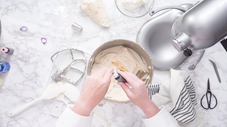 Mixing ingredients in standing kitchen mixer to make buttercream frosting.