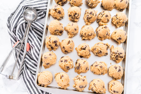 Homemade chocolate chip cookies dough scoops on a baking sheet.