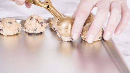 Step by step. Scooping homemade chocolate chip cookies with metal dough scoop to the baking sheet.