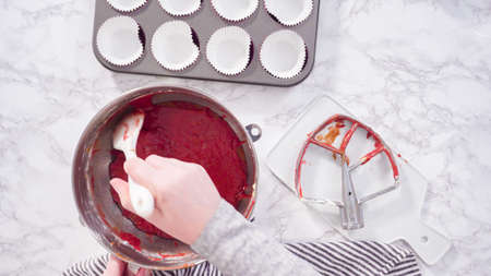 Flat lay. Step by step. Scooping cupcake batter into foil cupcake cups to bake red velvet cupcakes.の写真素材