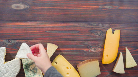 Flat lay. Large wedges of gourmet cheese on a rustic wood background.の写真素材