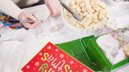 Step by step. Packaging homemade fudge and cookies into a Christmas gift box.