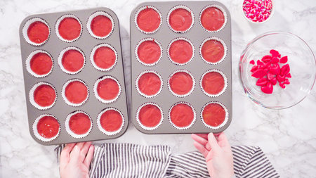 Flat lay. Step by step. Scooping cupcake batter into foil cupcake cups to bake red velvet cupcakes.