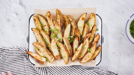 Flat lay. Step by step. Preparing russet potatoes in wedges with olive oil and spices to bake in the...