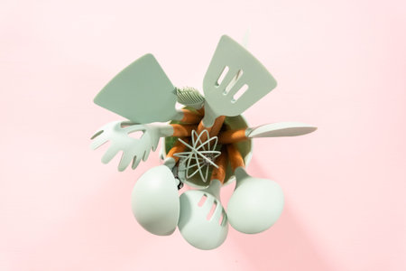 Flat lay. New blue silicone kitchen utensils with wooden handles on a pink background.