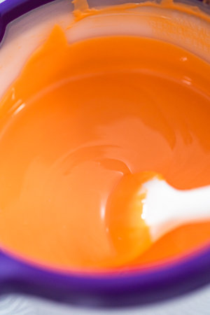 Melting color chocolate chips in a candy melting pot to make carrot chocolate-covered pretzels.の写真素材