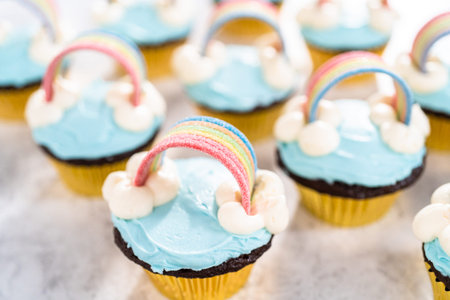 Chocolate cupcakes decorated with blue buttercream frosting and rainbow for unicorn theme birthday...
