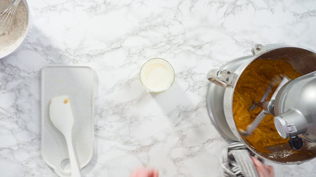 Flat lay. Mixing ingredients in electric kitchen mixer to bake pumpkin spice cupcake.