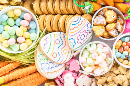 Assembling charcuterie board with Easter candies, cookies, and marshmallows.