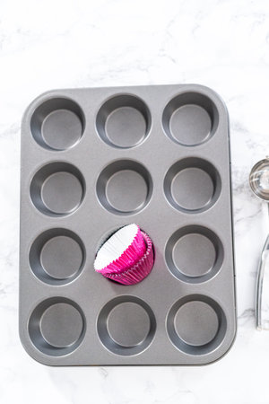 Baking chocolate cupcakes. Lining metal cupcake pan with foil cupcake liners.
