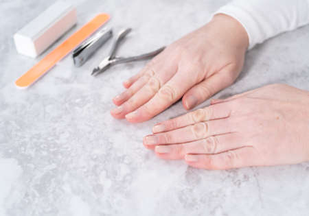 Woman finishing her manicure at home with simple manicure tools.の写真素材
