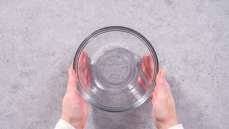 Flat lay. Step by step. Mixing ingredients in a glass mixing bowl to prepare the white glaze.の写真素材
