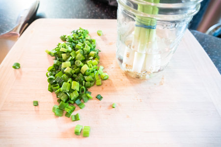Cutting organic green onions on a wood cutting board.