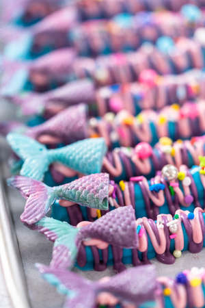 Mermaid chocolate pretzel rods drizzled with pink and purple chocolate and covered with sprinkles.の写真素材
