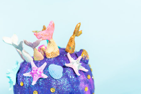 Halloween craft pumpkins decorated with mermaid tails, glitter, and sparkly rhinestones on a blue...