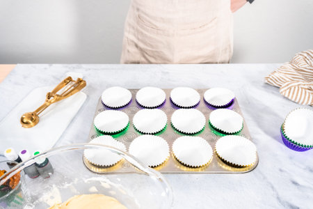 Vanilla cupcake batter in foil cupcake liners to bake Mardi Gras vanilla cupcakes.
