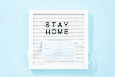 STAY HOME sign on message board with a blue medical mask.