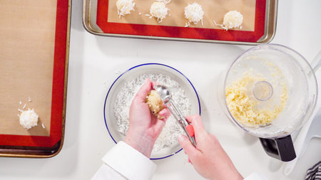 Flat lay. Scooping cookie dough into the baking sheet to bake coconut cookies.