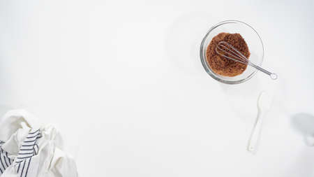 Flat lay. Mixing ingredients in a glass bowl to prepare glace for homemade cinnamon rolls.の写真素材