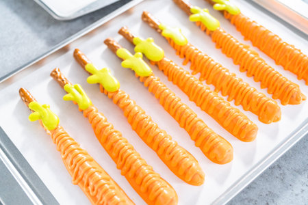 Dipped in chocolate pretzel rods on a baking sheet with parchment paper.
