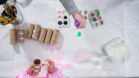 Flat lay. Kids papercraft. Painting empty toilet paper rolls with acrylic paint to create paper...