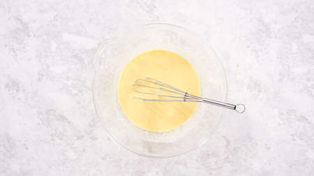 Flat lay. Step by step. Mixing ingredients in a glass mixing bowl to prepare red velvet bundt cake.の写真素材