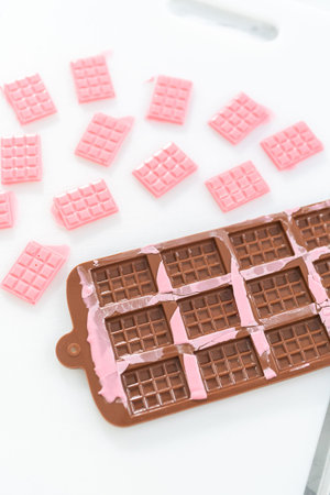 Removing mini pink chocolates from silicone chocolate mold.