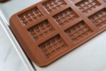 Filling silicone chocolate mold with melted chocolate to make mini pink chocolates.の写真素材