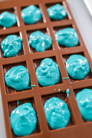 Filling in chocolate silicone molds with melted chocolate to preparing mini mermaid chocolate bars.の写真素材