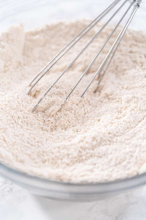 Mixing ingredients in a large glass mixing bowl to bake pumpkin bunt cake.の写真素材