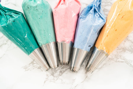 Piping bag with metal tips filled with colorful Italian buttercream frosting.の写真素材