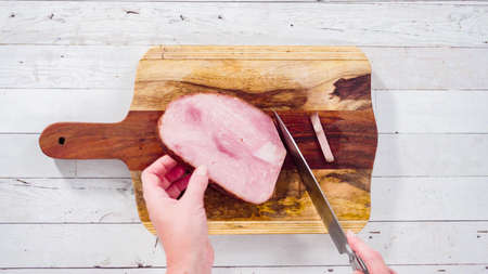 Flat lay. Cutting organic honey ham on a wood cutting board.の写真素材