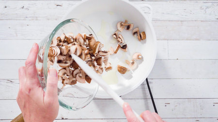 Flat lay. Sauteed organic baby bella mushrooms in a white frying pan.