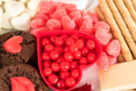 Valentines Day cheese board with a variety of cookies and candies.