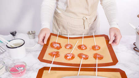 Step by step. Peeling cooled homemade lollipops from silicone baking mats.の写真素材