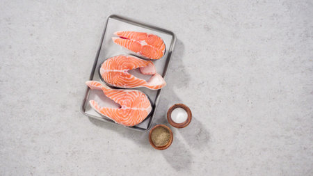 Farm-raised salmon steaks on a cooking tray with a parchment paper.
