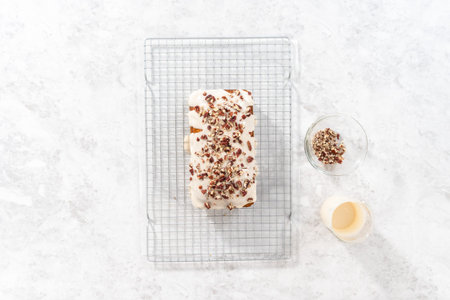 Flat lay. Glazing pumpkin bread with a white glaze and garnishing with shopped pecans.