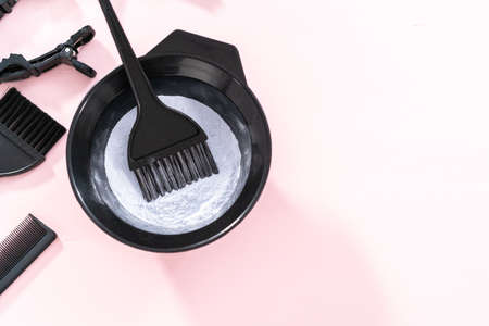 Hair color dye powder in a black plastic mixing bowl on a pink background.の写真素材