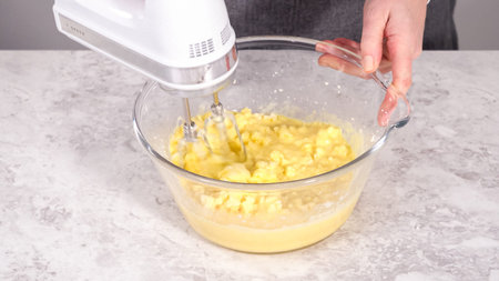 Step by step. Mixing ingredients in a glass mixing bowl to prepare red velvet bundt cake.