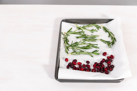 Covering fresh cranberries and rosemary in sugar to decorate chocolate bundt cake with chocolate frosting.の写真素材