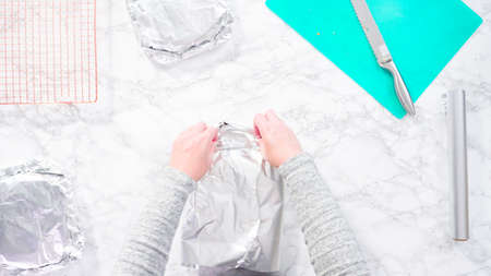 Flat lay. Step by step. Wrapping freshly baked funfetti cake into cellophane and cooking foil for freezer storage.の写真素材