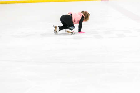 Little girl practicing figure skating moves on the indoor ice rink.の写真素材