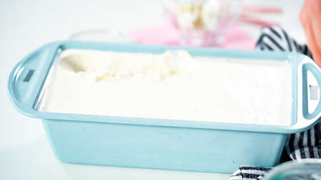 Scooping homemade coconut ice cream into a glass ice cream bowl.の写真素材