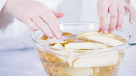 Step by step. Soaking potato wedges in a bowl of water to prepare baked potato wedges with spices.の写真素材