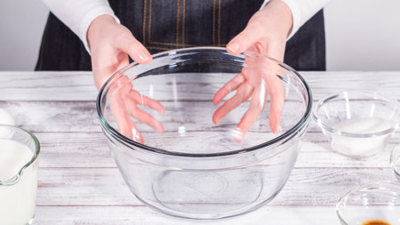 Step by step. Mixing ingredients in a large glass mixing bowl to prepare French toast.