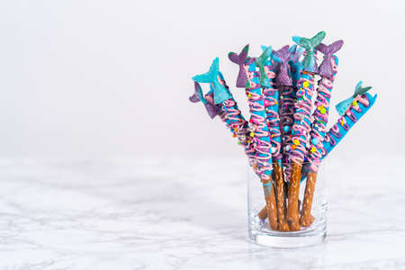 Mermaid chocolate pretzel rods drizzled with pink and purple chocolate and covered with sprinkles.の写真素材