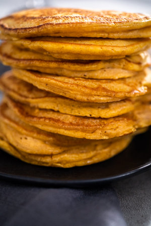 Stack of fresh pumpkin pancakes on a black plate.