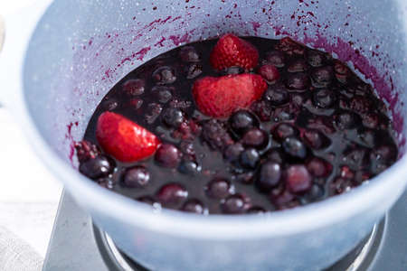 Preparing mixed berry compote from frozen berries in a nonstick cooking pot.の写真素材