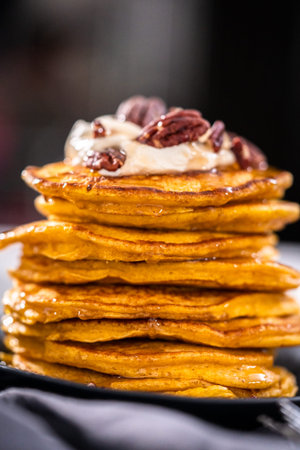 Stack of fresh pumpkin pancakes on a black plate.