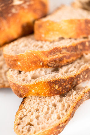 Slicing freshly baked sourdough rye bread on a white cutting board.